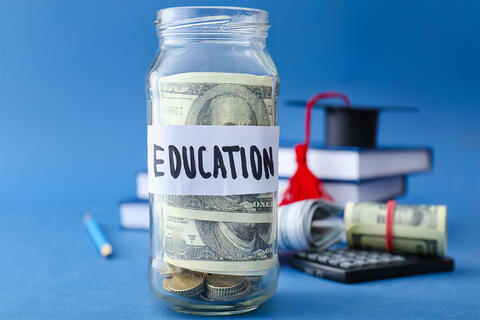 A jar with a hundred dollar bill inside and a label on the jar that says "education"