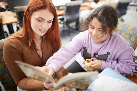 A UNLV student reads a book with a Paradise Elementary student.