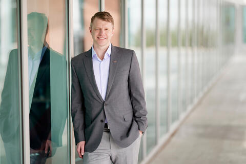 man leaning against an exterior wall of paneled windows