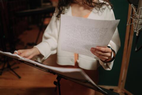 cropped photo of woman holding paper with lyrics on it