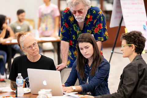 A group of people looking at a laptop
