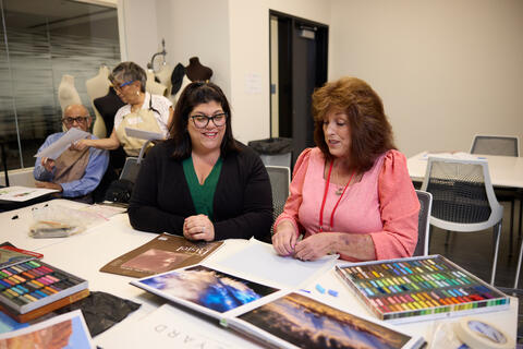 two women at a desk looking over photos and color samples