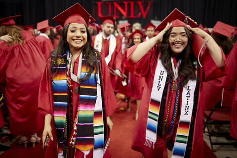 two women in graduation gowns with "UNLV Latinx" Stolls