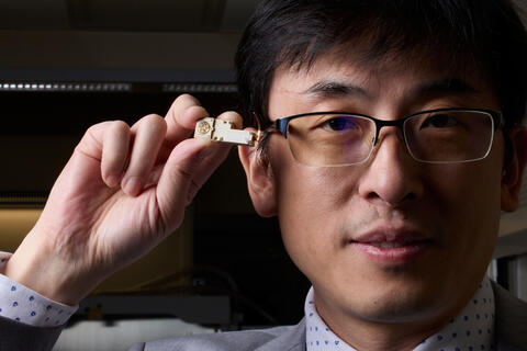 man holding small engineered device close to face