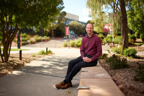 man sitting on stone partition on UNLV campus