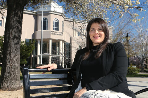 woman sitting on bench in front of nevada state legislature building