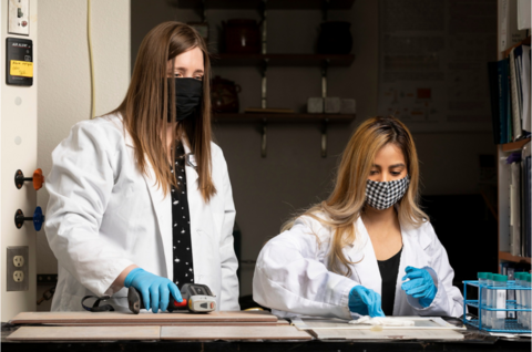 two people wearing lab coats and masks