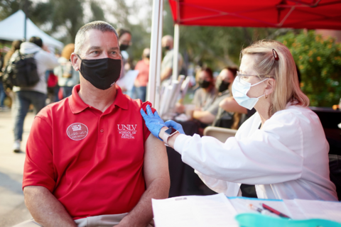 a person of healthcare giving an immunization shot to a patient