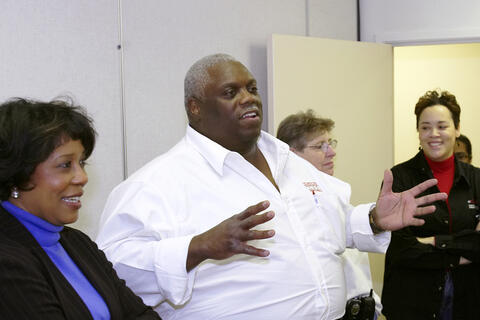 William Sullivan wearing a white shirt and speaking to a small group in a room