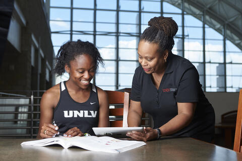 person on the left showing another person something on a paper