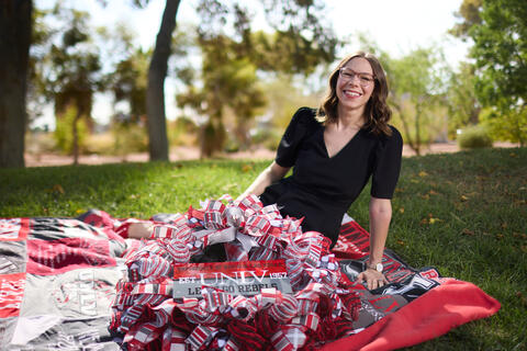 woman sits on quilt made of shirts with wreath in her lap