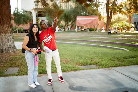 A man using their arm to point in a direction while a woman is looking towards that direction