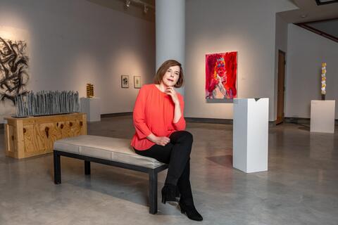 Painter and UNLV professor Wendy Kveck sits on a bench in a UNLV art gallery