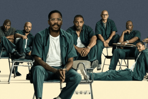 men in prison uniform sitting in chairs and on floor