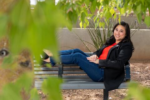UNLV alumna Aileen Pastor relaxes on a park bench on campus with her feet up