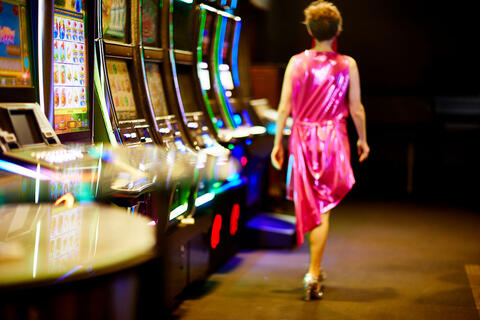 A woman in a pink dress walking down a pathway with slot machines on the left