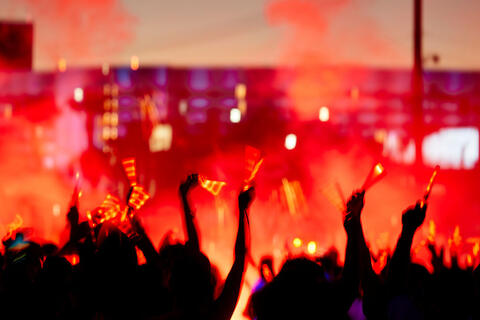 A crowd raising their arms up outside at an event