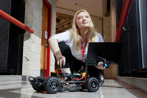 Person sitting on the floor holding a laptop