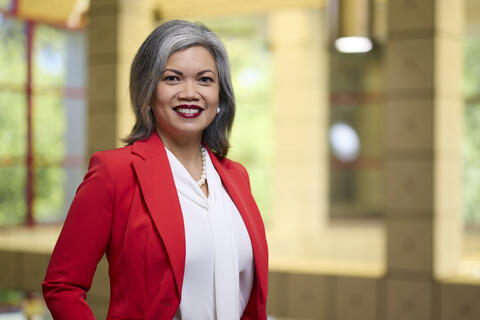 woman in red suit jacket and white blouse smiling