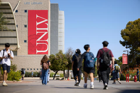 students walking with library in the background