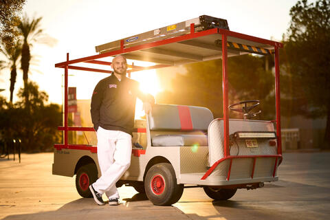 A portrait of Casey Sierra, paint shop supervisor, with his golf cart and painting materials.