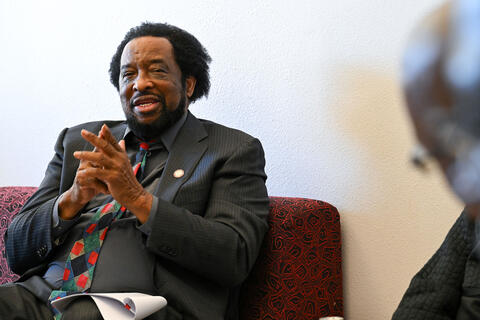 man seated with hands clasped