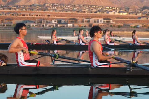 Students in a boat rowing on a body of water. 