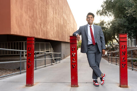 man posing by red metal pillars