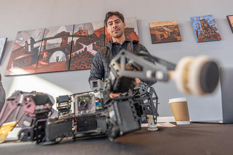 Young man standing behind a robot