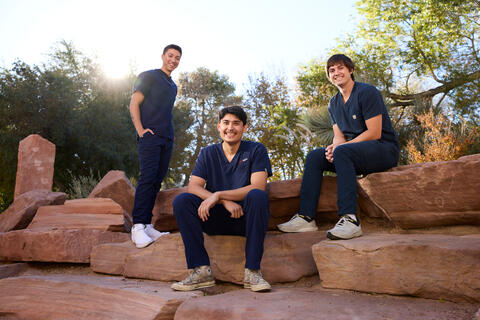 three physical therapy students sitting together on rocks