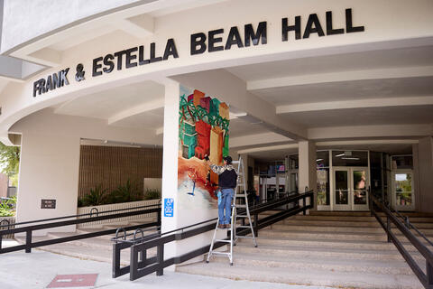 worker installing mural on building exterior
