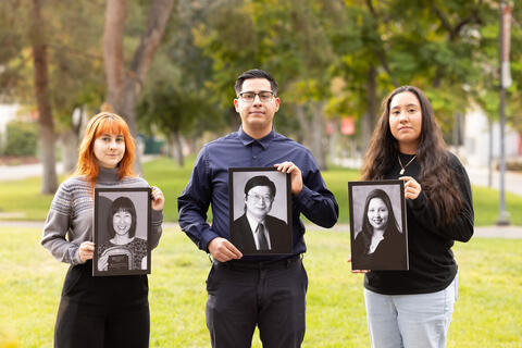 students hold framed photos of professors lost on Dec. 6