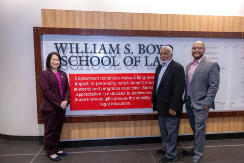 Dean Grinvald, Justice Douglas, and Will Sykes stand by law school signage