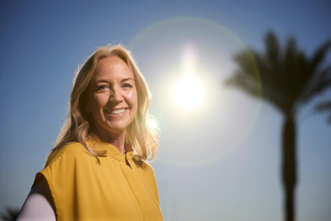 smiling woman in yellow shirt with sun in background