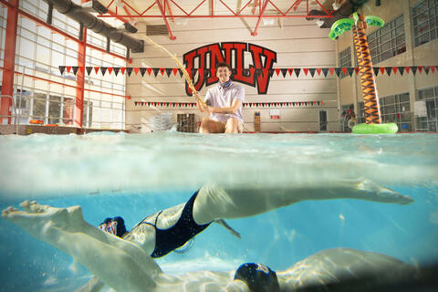 Hospitality student David Jelinksy fishes in the UNLV pool. Members of the UNLV Swim Team dive underneath the water.