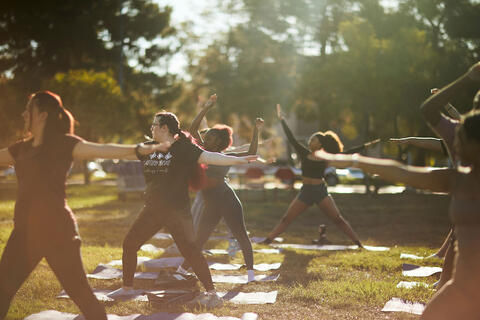 A group of people doing yoga outside in a grass area