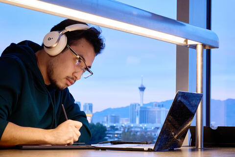 Student looking down at laptop with LV Strip in background