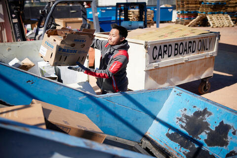 man placing carboard in bin for recycling