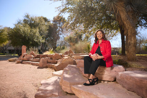 Lori Porter in red and black outfit sitting on a large stone