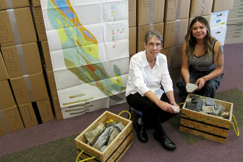 two women in front of map and rock samples
