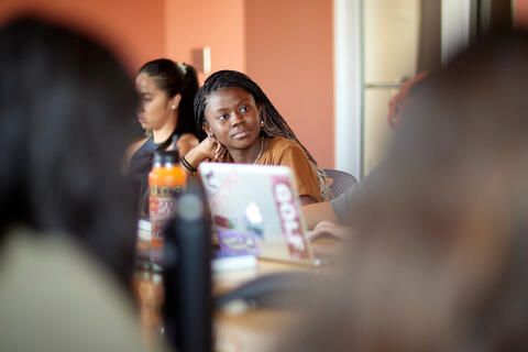 A woman in focus looking forward in a classroom
