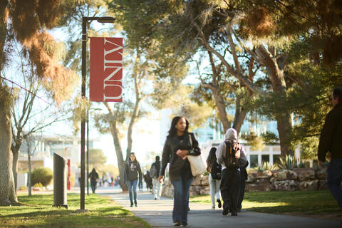 students walking on UNLV campus by banner and trees