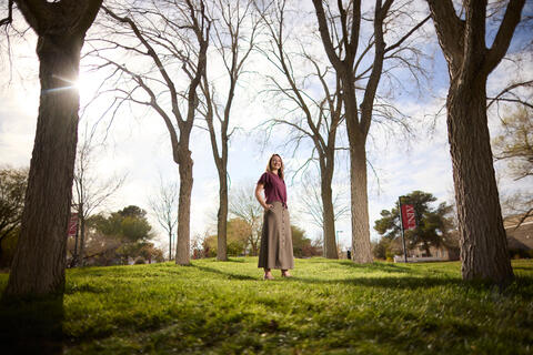 a faraway shot of Alissa Gardner standing between trees under the sunlight