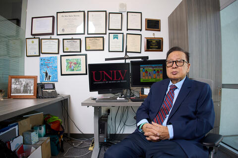 Francisco Sy in office by wall of framed diplomas and certificates