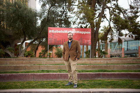 Nicholas Irwin in front of the Rebels Make It Happen banner