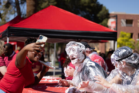 individual taking photo of person covered in pie