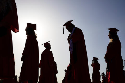 Silhouettes of people in graduation apparel