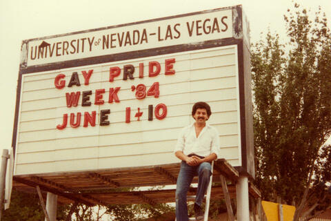 Will Collins in front of a marquee advertising a gay pride event in 1984 at UNLV