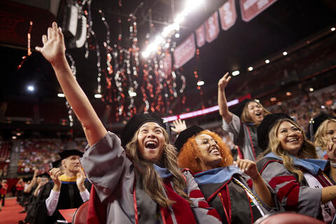 Graduates cheering with their arms raised