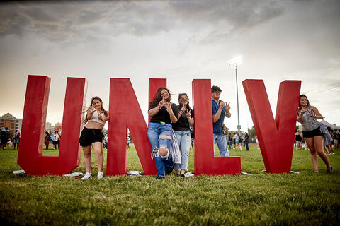U-N-L-V letters with people posing with it